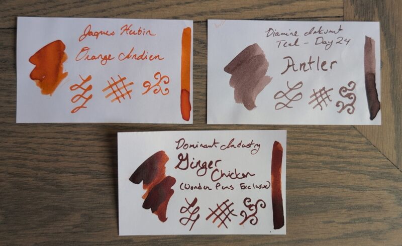 A set of three ink swatches: Jaques Herbin Orange Indien (bright orange), Diamine Antler (dusty pink-leaning brown) and Dominant Industry Ginger Chicken (deep orange-brown with shading)