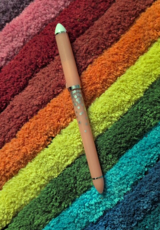 A peach 30th anniversary Sailor Fude with birthday sparkles on it, set against a rainbow rug.