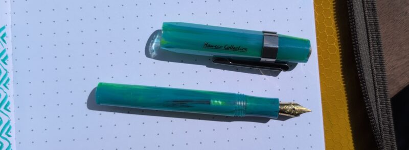 Kaweco Sport Ocean Breeze fountain pen. The pen is shown on white paper in bright sunlight so you can see that areas are translucent, enough so that you can see the ink inside the pen and the shadow is clear-ish in spots.