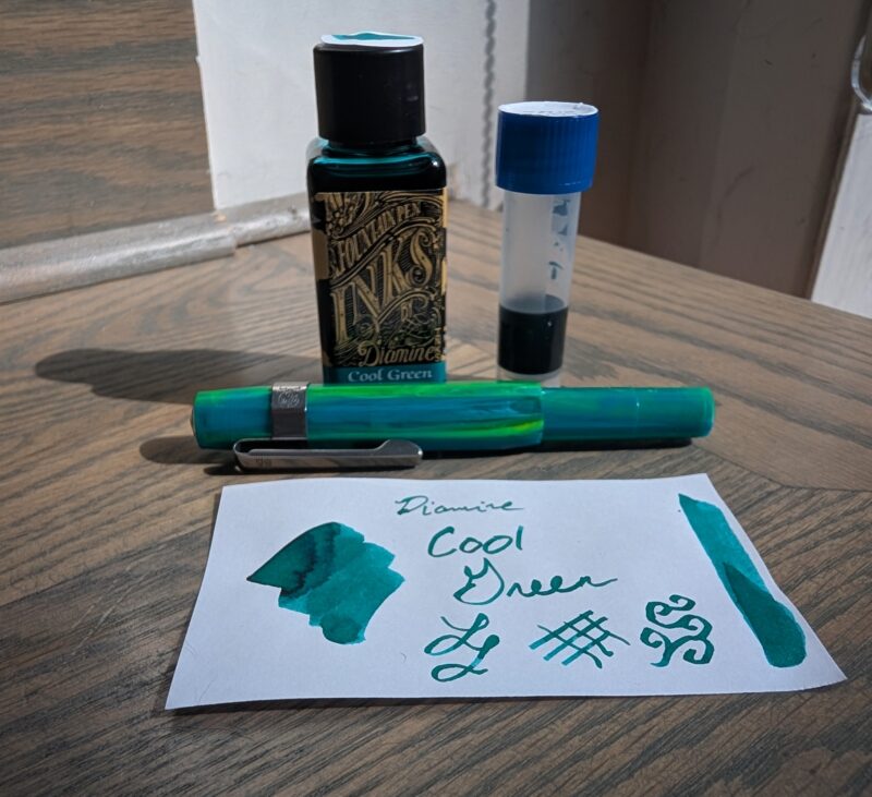 Diamine Cool Green fountain pen ink with swatch, 2ml in a vial that I spilled on the table, and Kaweco Sport pen in "Marble Ocean"