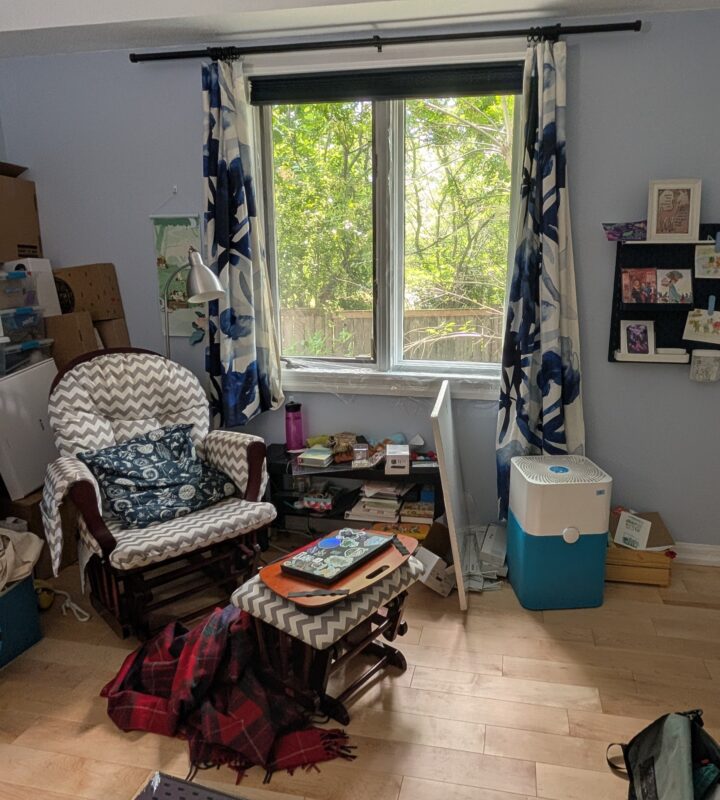 My reading/writing area in my office by the window, showing lots of mess but also the new curtains, the comfy glider chair, and the pegboard art setup on the wall.