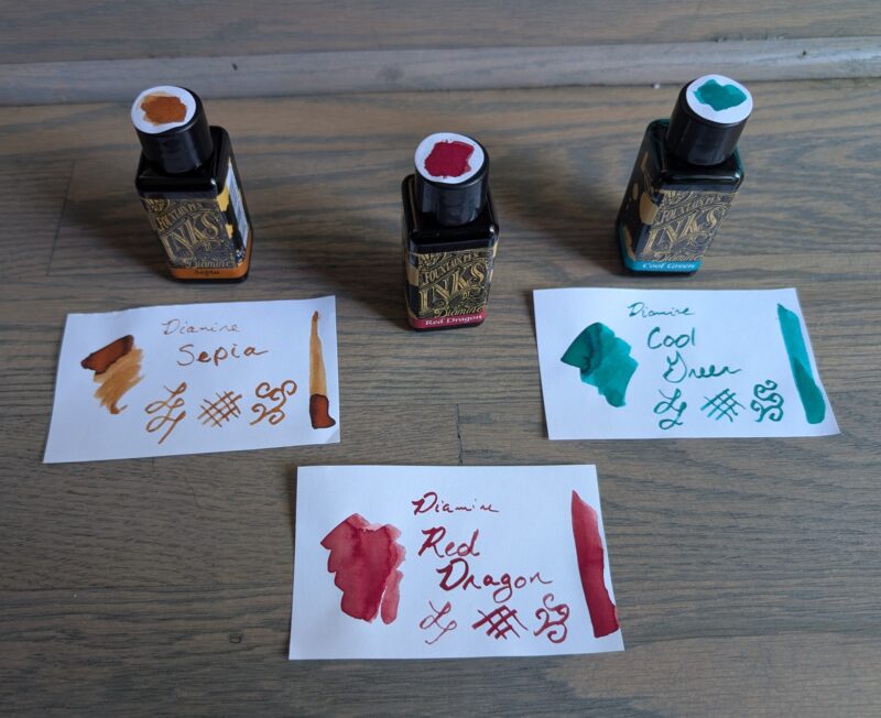 Three fountain pen inks from Diamine with swatches. From left to right the inks are named Sepia, Red Dragon, and Cool Green.